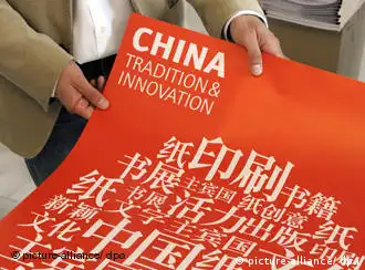 A man holds a poster from the Frankfurt International Book Fair with Chinese script