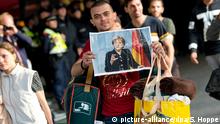ARCHIV - Ein Flüchtling, der kurz zuvor mit einem Zug angekommen ist, läuft am 05.09.2015 auf dem Hauptbahnhof in München (Bayern) über den Bahnsteig und hält dabei ein Foto von Angela Merkel in den Händen. (zu dpa Regierung: Bundestag war in Flüchtlingskrise ausreichend involviert vom 22.09.2017) Foto: Sven Hoppe/dpa +++(c) dpa - Bildfunk+++ | Verwendung weltweit
