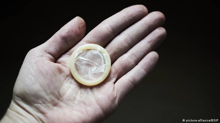 A condom is held in the palm of a hand