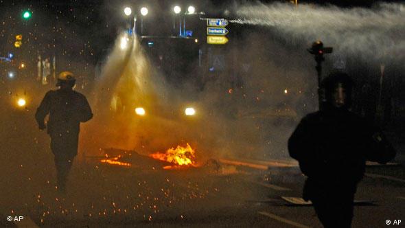 Polizisten laufen durch eine Straße mit brennenden Barrikaden (Foto: AP)