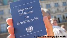 Ein Mitglied von amnesty international hält am Samstag (10.05.2008) in Hamburg während einer Aktion der Menschrechtsorganisation ein Heft mit der Allgemeinen Erklärung der Menschenrechte in der Hand. Vor knapp 60 Jahren, am 10.12.1948, verabschiedete die Generalversammlung der neu gegründeten UN die Allgemeine Erklärung der Menschenrechte - den ersten weltweit geltenden Menschenrechtskatalog. Sie bildet die Grundlage der Arbeit von amnesty international. Foto: Bodo Marks dpa/lno +++(c) dpa - Report+++ | Verwendung weltweit