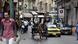 A horse and carriage rides alongside cars in a street A horse and carriage rides alongside cars in a street