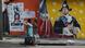 Women walk past a colorful mural in Miami's Little Haiti neighborhood Women walk past a colorful mural in Miami's Little Haiti neighborhood