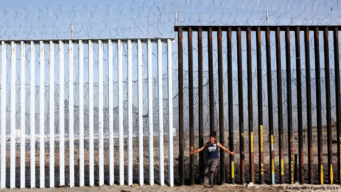 Foto simbólica de una migrante que se apoya en la valla fronteriza