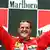 Schumacher, com uniforme de piloto, com os dois braços levantados num momento de comemoração