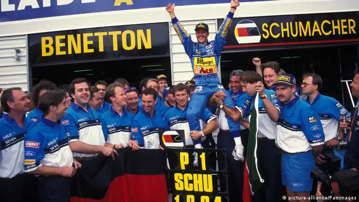 Michael Schumacher alza los brazos, en andas, y rodeado de gente.