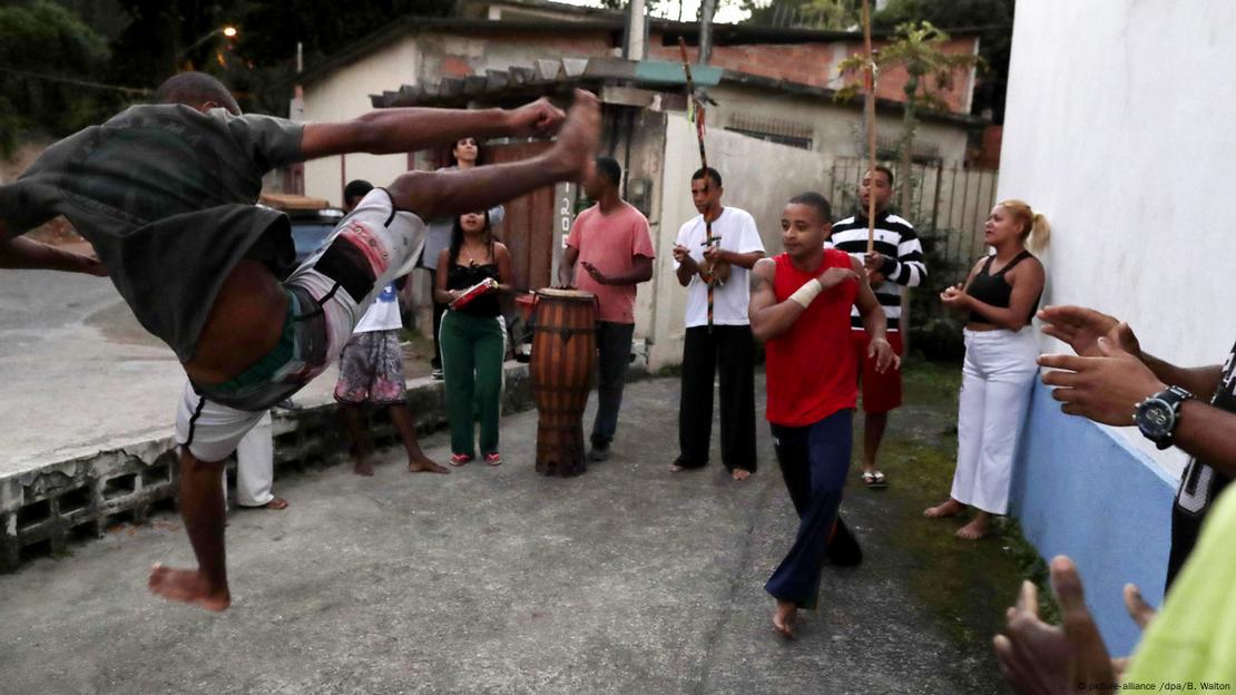 Roda de capoeira com homens jogando e tocando berimbau