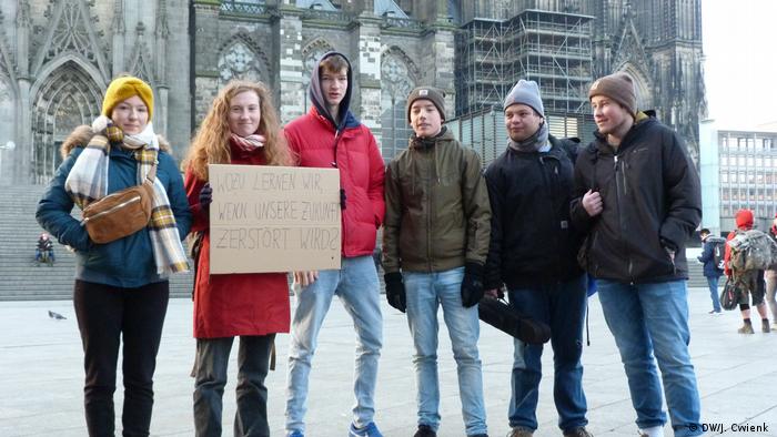 Six students stand in a row an pose for the camera during a protest in the main square next to the Cologne Cathedral. 