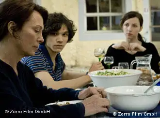 Eine ältere Frau, eine junge Frau und ein junger Mann sitzen am Tisch und essen, Szene aus Es kommt der Tag (Zorro Film)