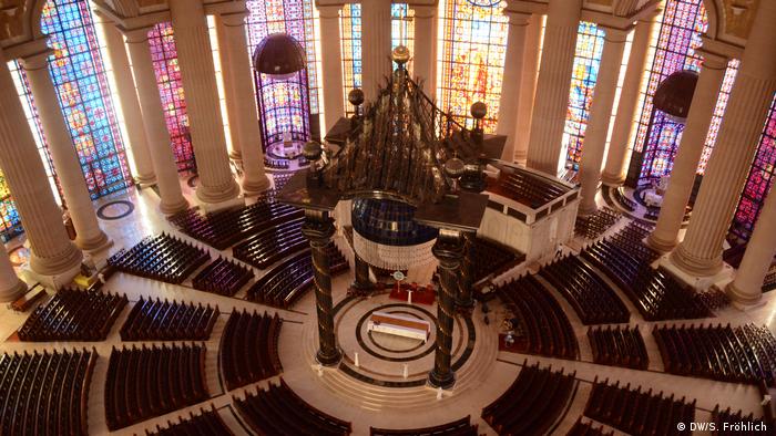 Ein Blick in das Innere der Kirche. Kreisförmig angereihte Bänke gruppieren sich um den Altar