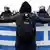 A protester holds up a Greek flag in front of police officers in Athens, Greece