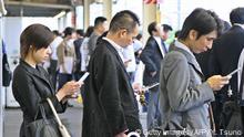 Commuters check websites or e-mail through their mobile phones as they wait for a train at a Tokyo station on September 14, 2006. AFP PHOTO/YOSHIKAZU TSUNO (Photo credit should read YOSHIKAZU TSUNO/AFP/Getty Images)