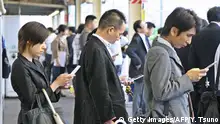 Commuters check websites or e-mail through their mobile phones as they wait for a train at a Tokyo station on September 14, 2006. AFP PHOTO/YOSHIKAZU TSUNO (Photo credit should read YOSHIKAZU TSUNO/AFP/Getty Images)