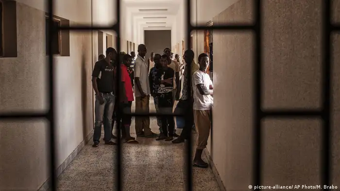 Migrants stand in a hall at a detention center for migrants, in the village of Karareem