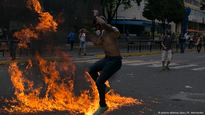 Un hombre se ve amenazado por el fuego durante protestas en Caracas. (23.01.2019).