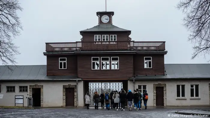 People stand outside the gates of the former concentration camp of Buchenwald. 