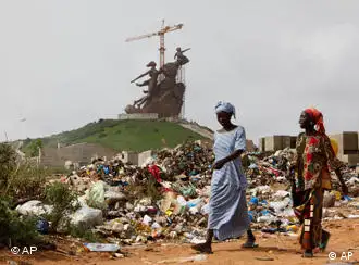 In this photo taken Monday, Sept. 21, 2009, women walk past ruubbish heaps and unfinished homes in a neighborhood at the base of the nearly-completed 50-meter-high (328-foot-high) bronze statue dubbed the Monument of the African Renaissance in Dakar, Senegal. The statue is supposed to symbolize Africa's rebirth, its liberation from what octogenarian President Abdoulaye Wade has called centuries of ignorance, intolerance and racism. Instead, the monument has fueled outrage among a poverty-stricken population struggling to survive in an expensive city slammed by electricity blackouts, flooding and water shortages. (AP Photo/Rebecca Blackwell)