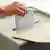 A hand places a ballot into a ballot box