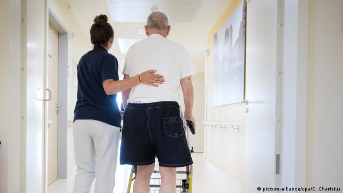 A nurse helps an old man