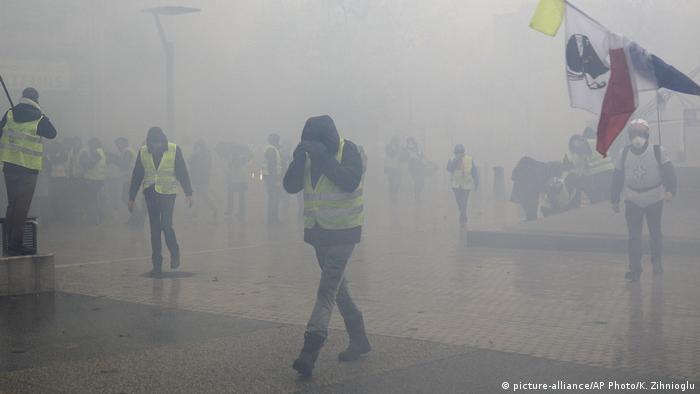 Protesters shield their faces from tear gas during 'yellow vest' protests in Paris (picture-alliance/AP Photo/K. Zihnioglu)