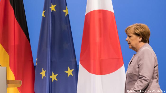 Angela Merkel mit Flaggen von Deutschland, der EU und Japan