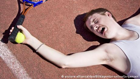 Ein Mann liegt mit einem Tennisschläger auf dem Boden und verzieht das Gesicht (picture-alliance/dpa/Bildagentur-online/Jorgensen)