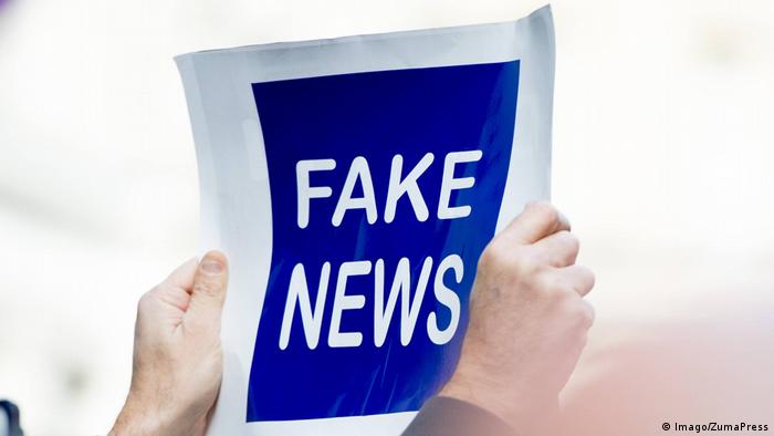 A person holds up a sign reading Fake News
