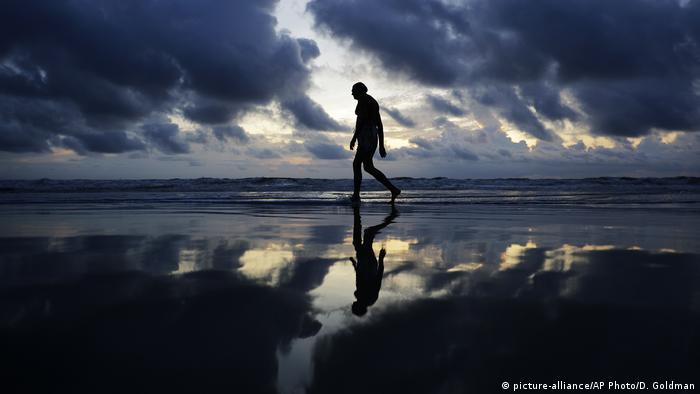 A man walks along the beach at sunrise ahead of Hurricane Irma in Daytona Beach, Florida