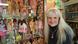A woman smiles while standing next to a case of lots of Barbies A woman smiles while standing next to a case of lots of Barbies