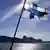 A Finnish flag flies from a ship on a body of water