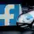 Смартфон с отражением логотипа Facebook, очки и клавиатура