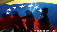 Venezuelans living in Costa Rica cast shadows on a Venezuelan flag during a rally in support of Venezuela's opposition leader Juan Guaido, in San Jose, Costa Rica February 2, 2019. REUTERS/Juan Carlos Ulate