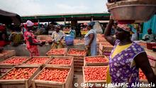 A woman sells tomatoes to a costumer at her stand at the Agbogbloshie market, Accra, June 28, 2018. - Tomato is used in plenty of Ghanaian dishes or eaten raw as a tomato and onion salad. The Agbogbloshie neighbourhood is internationally known as having one of the biggest electronic wastes in the world. (Photo by CRISTINA ALDEHUELA / AFP) (Photo credit should read CRISTINA ALDEHUELA/AFP/Getty Images)