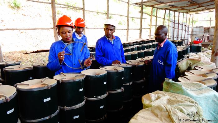 Eine Frau und mehrere Männer bei der Herstellung von effizienten Öfen in Ruanda