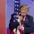 US President Donald Trump hugs the US flag during CPAC 2019