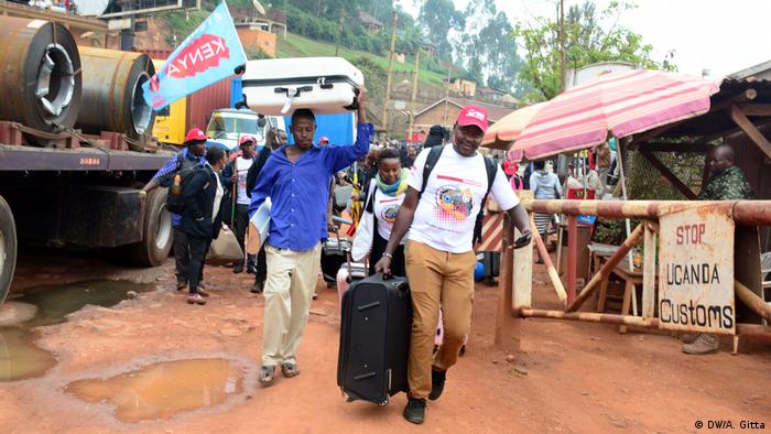 People walk past Ugandan border into Rwanda.