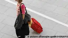 Frau zieht roten Trolley hinter sich her, Flughafen Düsseldorf, NRW, Deutschland, Europa | Verwendung weltweit, Keine Weitergabe an Wiederverkäufer.