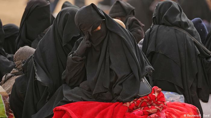A woman sits on a blanket near Baghouz, Iraq