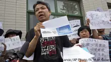 Jiang Hui whose mother was on board the missing Malaysia airplane MH370 holds up pictures showing plane parts suspected to belong to the missing plane after attending the presentation of a report written by a 19-member international team in Beijing, China, Friday, Aug. 3, 2018. The relatives said Friday they refuse to accept the latest report on the plane's disappearance four years ago and demand the search be restarted. (AP Photo/Ng Han Guan) |