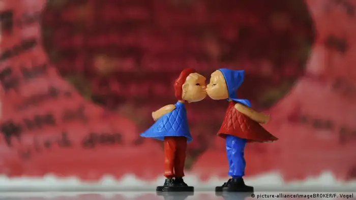 Little toy figures kissing with red and blue caps on. 