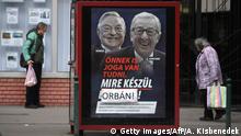 People walk past a poster on a telephone booth showing the portraits of European Commission chief Jean-Claude Juncker (R) and Hungarian-born US investor and philanthropist George Soros and a slogan reading You too have a right to know what Brussels is preparing as the name Brussels is covered by the family name of Hungarian Prime Minister Orban in Budapest on February 26, 2019. - Opposition activists in Hungary on February 25, 2019 defaced hundreds of posters put up by the government of nationalist Prime Minister Viktor Orban attacking European Commission chief Jean-Claude Juncker and billionaire George Soros. (Photo by ATTILA KISBENEDEK / AFP) (Photo credit should read ATTILA KISBENEDEK/AFP/Getty Images)