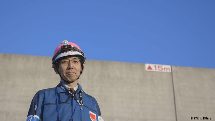 Toshimitsu Tamai standing in front of the tsunami protection wall at the Kashiwazaki-Kariwa plant