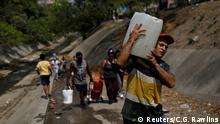 People carry plastic containers with water collected from a sewage drain that feeds into the Guaire River, which carries most of the city's wastewater, in Caracas, Venezuela March 11, 2019. REUTERS/Carlos Garcia Rawlins