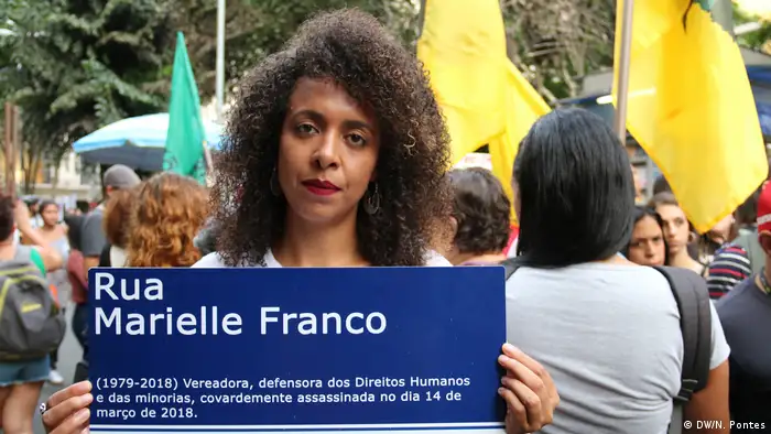 Mulher carrega placa de rua com o nome de Marielle Franco