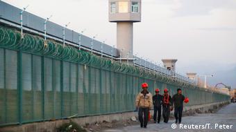 Workers walk by the perimeter fence of what is officially known as a vocational skills education centre, under construction in Dabancheng in Xinjiang Uighur Autonomous Region, China September 4, 2018.