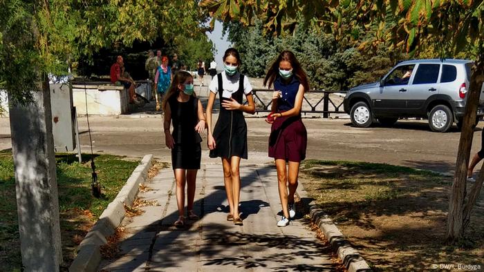 Schoolgirls from the Kherson village of Preobrazhenka in protective masks return home after classes are canceled