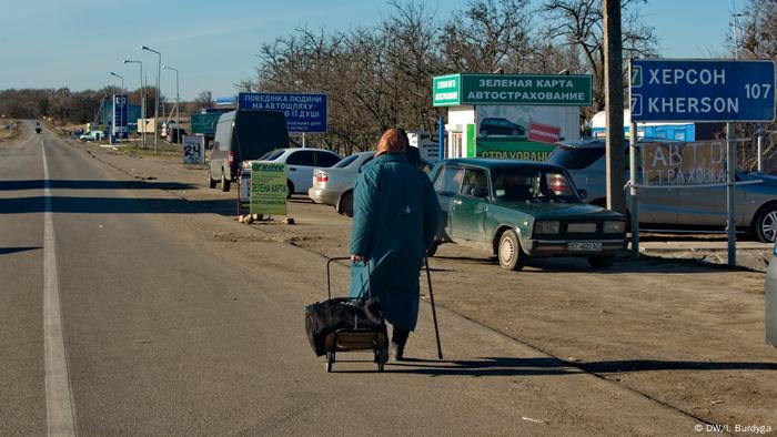 An elderly woman with a bag walks in the direction of Crimea near the administrative boundary line