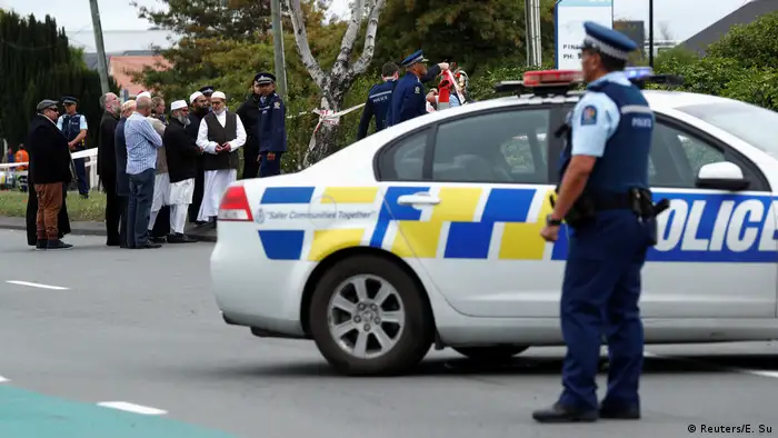 Police stand guard as members of Muslim religious groups gather for prayers at the site of the shooting outside Linwood Mosque in Christchurch