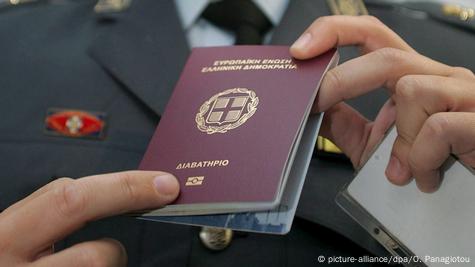 Службеник во темно одело со двете раце држи грчка патна исправа Службеник во темно одело со двете раце држи грчка патна исправа