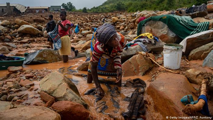 An elderly woman washes her belongings in the mud after Hurricane Ida hit Mozambique.